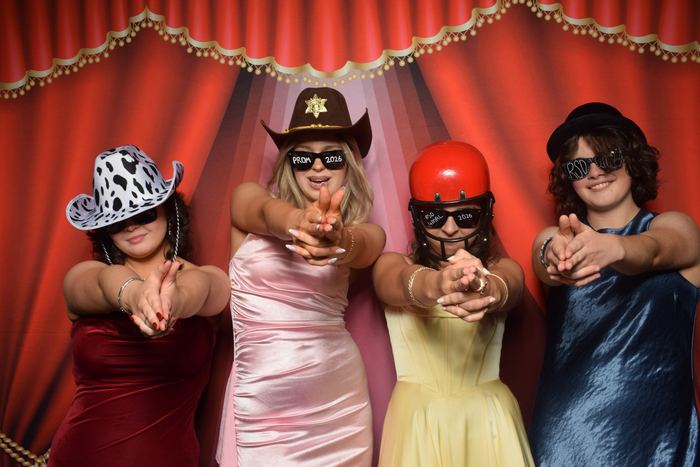 Friends with props at the red curtain photo booth